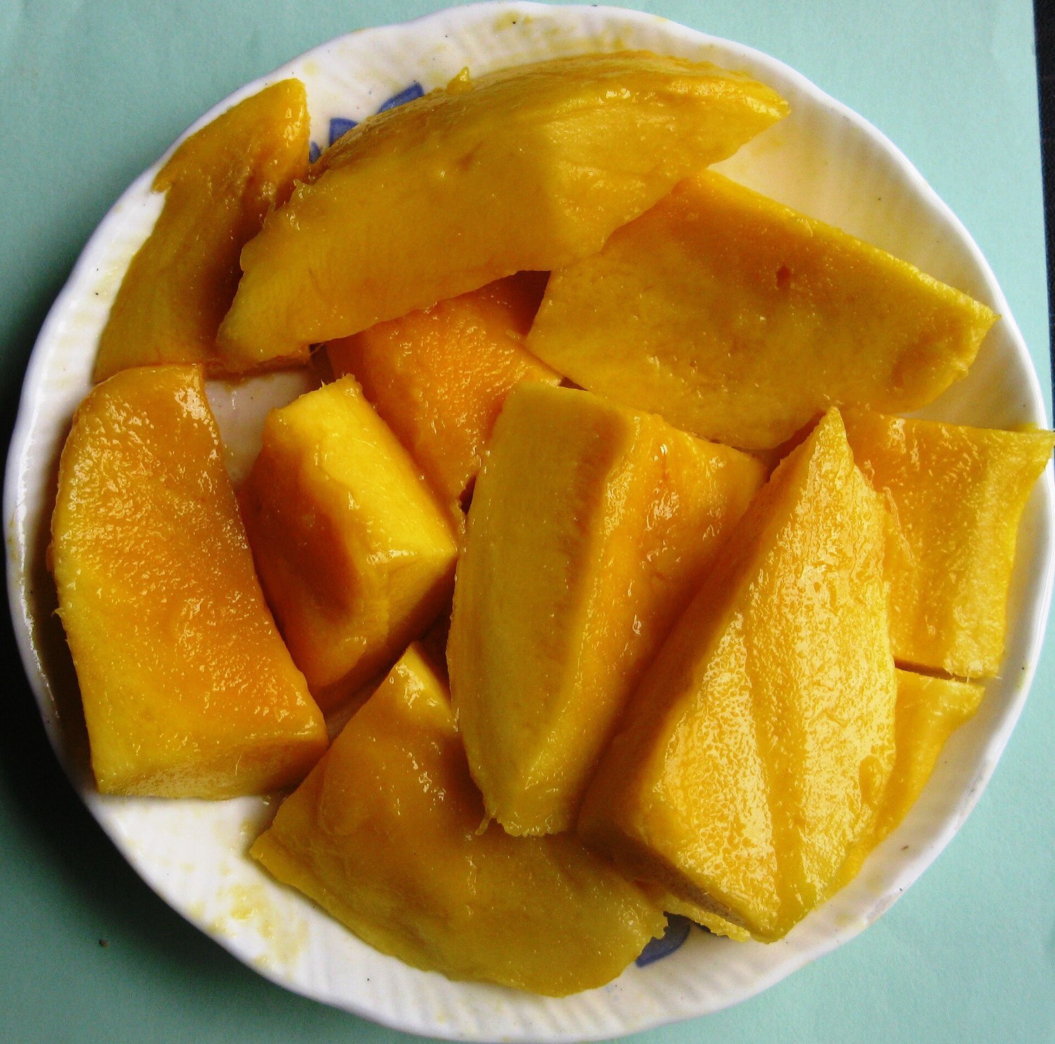 Ripe mango, peeled and cut into chunks in a white bowl.